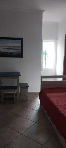 a bedroom with a bed and a table and a window at Apartamento de frente ao mar - Centro in Peruíbe