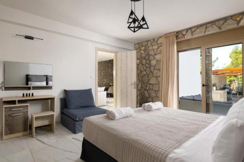 a bedroom with a bed and a chair and a television at Drakos Estate - Luxury Pool Villas in Asgourou