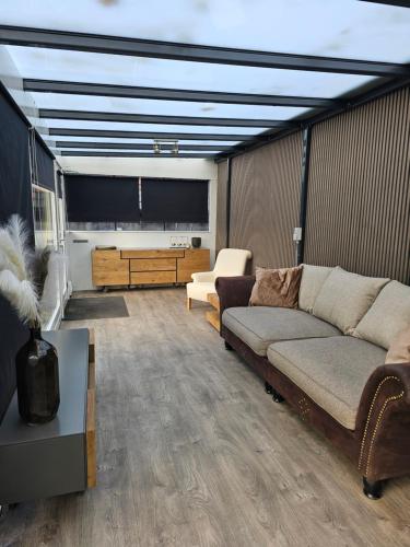 a living room with a couch and a flat screen tv at Houten Chalet nabij Beekse Bergen in Hilvarenbeek