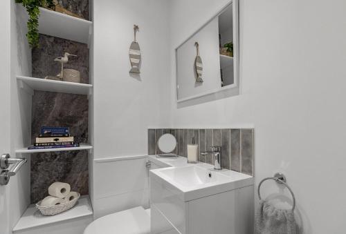 a white bathroom with a sink and a mirror at Quayside Marina in Torquay