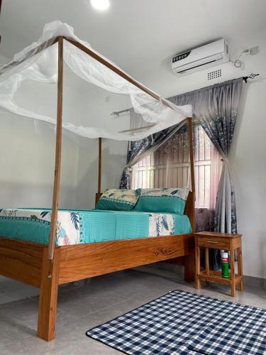 a bedroom with a wooden bed with a canopy at Carinho da Paz in Inhambane