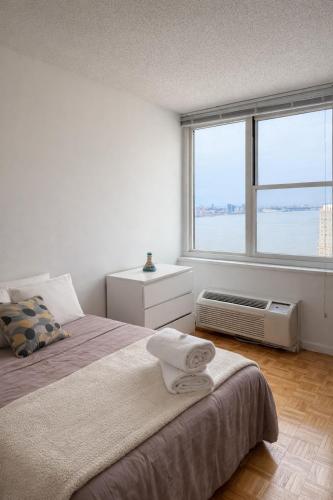 a bedroom with two beds and a large window at Skyline with Hudson Views Modern Battery Park Stay in New York