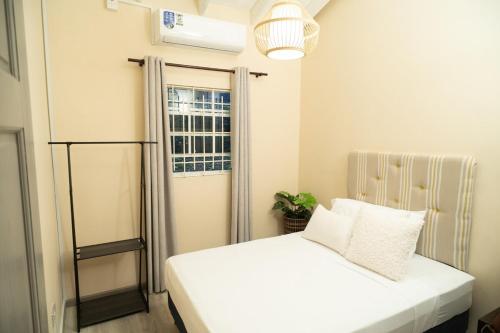 a small bedroom with a white bed and a window at Almond Tree Villa Beach Hideaway with Jacuzzi in Gros Islet