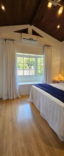 a bedroom with a bed and a large window at Quarto Familiar Centro in Pomerode