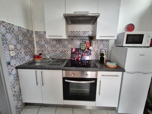 a kitchen with white cabinets and a sink and a microwave at appartement meublé romain in Niederbronn-les-Bains