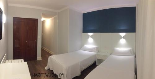 a bedroom with two beds and a blue overhead lamp at Hostal Vista Alegre in Castro-Urdiales