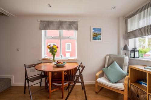 a living room with a table and chairs and a vase of flowers at Riverside Bothy In Heart of Scenic Harbour Village in Solva