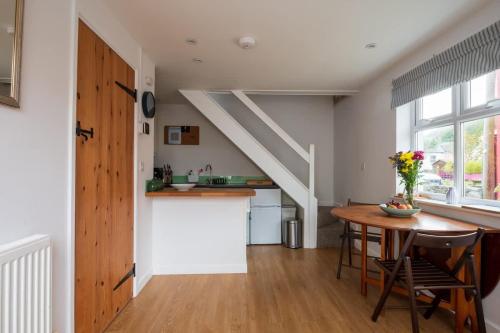 a kitchen and dining room with a table and a staircase at Riverside Bothy In Heart of Scenic Harbour Village in Solva