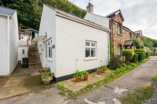 a white house with plants on the side of it at Riverside Bothy In Heart of Scenic Harbour Village in Solva