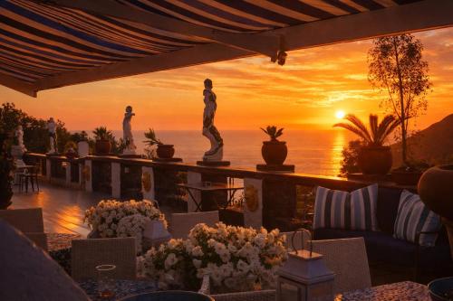 a view of a sunset from a restaurant with a statue at Hotiday Villa Neptunus in Forio d'Ischia
