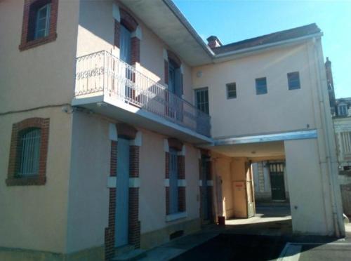 a white building with a balcony on the side of it at Hôtel de la gare - Petit Studio in Tarbes
