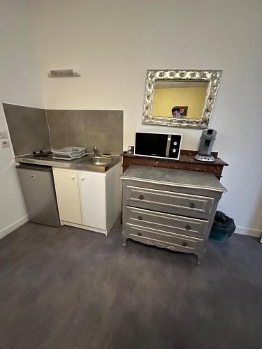 a kitchen with a sink and a mirror at Hôtel de la gare - Petit Studio in Tarbes