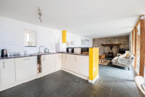 a kitchen with white cabinets and a living room at St Davids Hideaway with Roll-top Bath & Log Burner in St. Davids