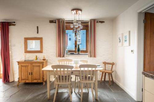 a dining room with a table and chairs and a window at St Davids Hideaway with Roll-top Bath & Log Burner in St. Davids