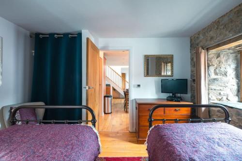 a bedroom with a bed and a television in it at Stunning Converted Granary in Heart of St Davids in St. Davids