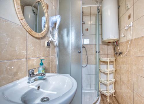a bathroom with a sink and a shower with a mirror at Domki parterowe ANITA in Zawóz