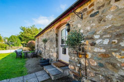a stone house with a white door and a patio at Cosy Farm Conversion In The Heart Of Pembrokeshire in Pembrokeshire