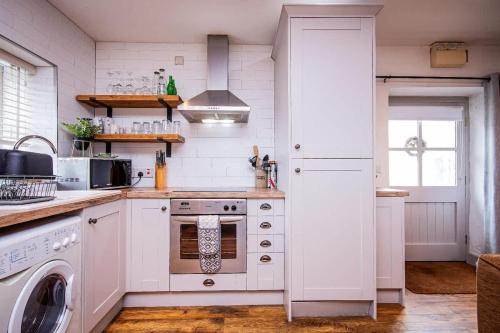 a kitchen with a stove and a washer and dryer at Cosy Farm Conversion In The Heart Of Pembrokeshire in Pembrokeshire