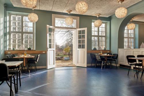 a dining room with tables and chairs and windows at Anneberg Gæstehus in Nykøbing Sjælland