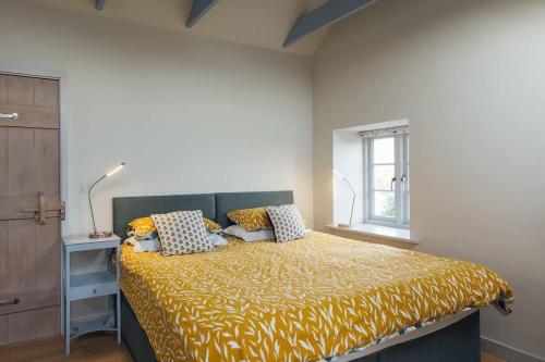 a bedroom with a bed with a yellow blanket at Converted Hay-loft with Stunning Countryside Views in Haverfordwest