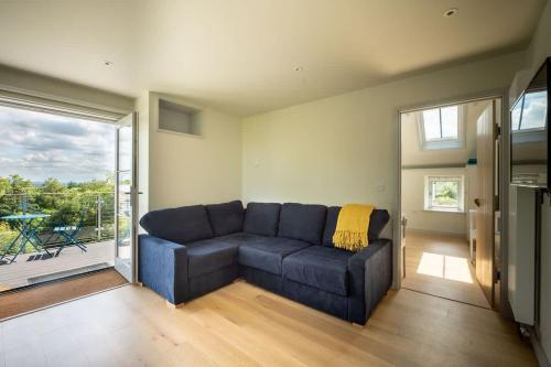 a blue couch in a living room with a large window at Converted Hay-loft with Stunning Countryside Views in Haverfordwest