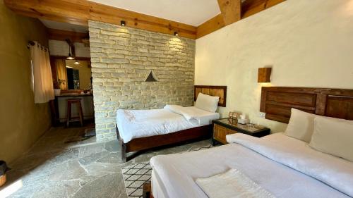 a bedroom with two beds and a brick wall at Bhanjyang Village Lodge in Pokhara