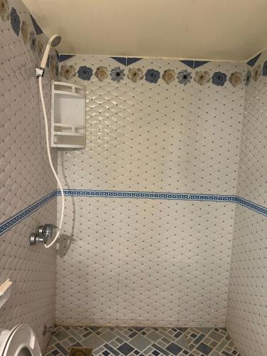 a bathroom with a toilet and a tiled wall at Merzouga Roms in Merzouga