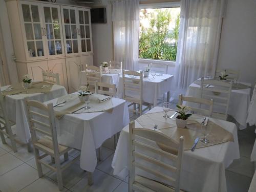 a dining room with white tables and chairs and a window at Pousada Casa de Campo in Conservatória