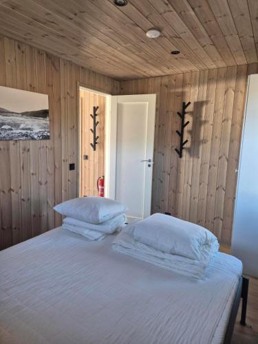 a bedroom with a white bed with wooden walls at Måvikens havsstugor in Måviken