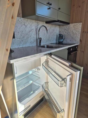 an open refrigerator with a sink in a kitchen at Måvikens havsstugor in Måviken