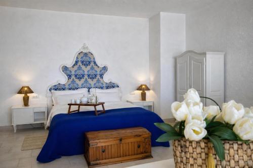 a bedroom with a blue and white bed and flowers at Hotiday Villa Neptunus in Forio d'Ischia