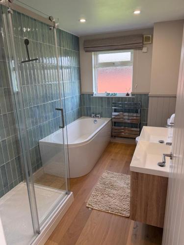 a bathroom with a tub and a shower and a sink at Lake View Lodge in Saint Columb Major