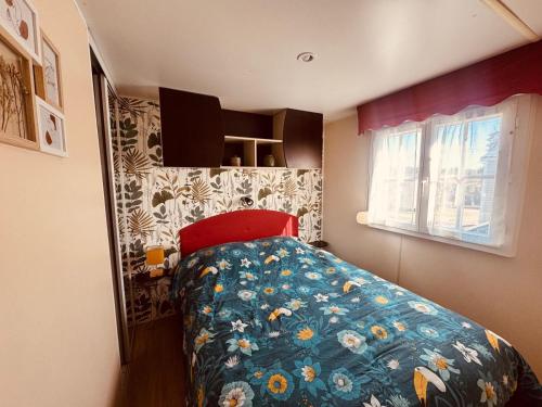 a bedroom with a bed with a blue comforter and a window at MH Camping la plage - MarieVa in Mimizan-Plage