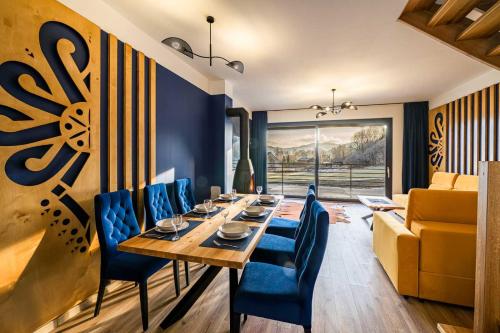 a dining room with a table and blue chairs at Chalety v Pieninách in Červený Kláštor