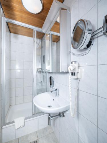 a bathroom with a sink and a shower and a mirror at DONAUHOTEL Ingolstadt in Ingolstadt