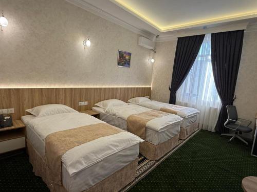 a hotel room with three beds and a window at Munir Hotel in Chilanzar