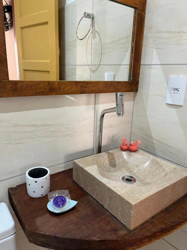 a bathroom sink with a mirror and a cup on a counter at Pedacinho do céu in Tiradentes