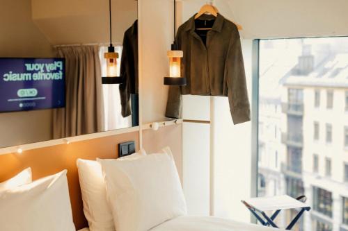 ein Schlafzimmer mit einem Bett und einem über einem Fenster hängenden Mantel in der Unterkunft Scandic Go, Grensen 20 in Oslo