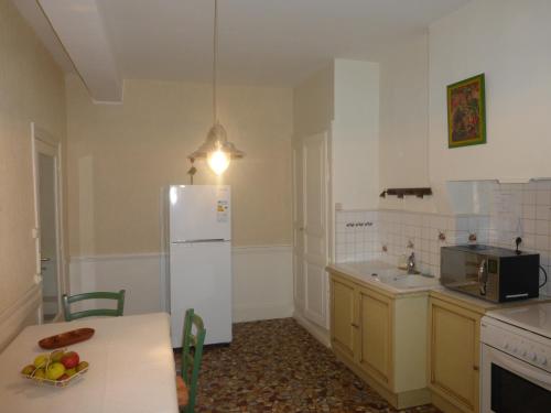 a kitchen with a white refrigerator and a table at Maison Commandant Blaison in Lapalisse
