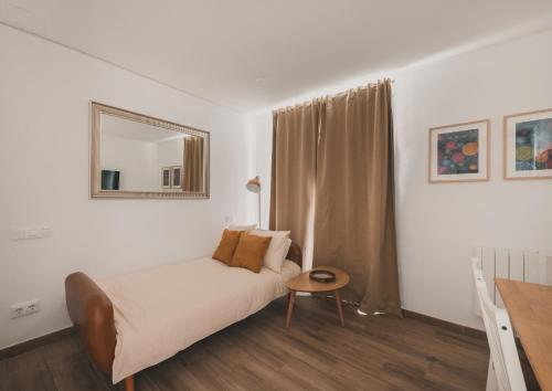 a white bedroom with a bed and a mirror at Alojamiento en Santa Eugenia A in Madrid