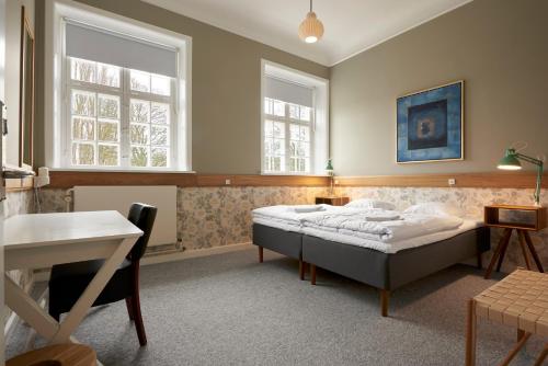 a bedroom with a bed and a desk and two windows at Anneberg Gæstehus in Nykøbing Sjælland