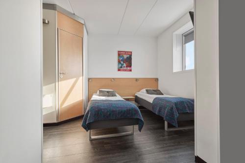 a bedroom with two beds and a mirror at Cabinn Metro in Copenhagen