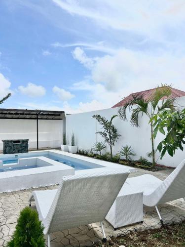 a backyard with a swimming pool and white chairs at Casa de Matilda in Silang