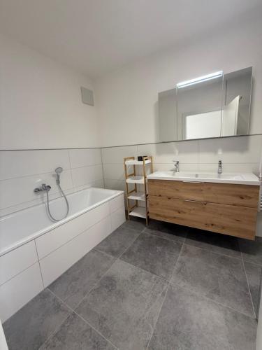 a bathroom with a tub and a sink and a mirror at Ferienwohnung Bad Schallerbach in Bad Schallerbach