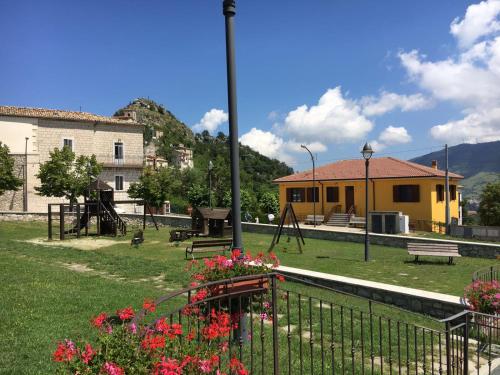 a park with a playground and a building and flowers at B&B La Torre in Rosello