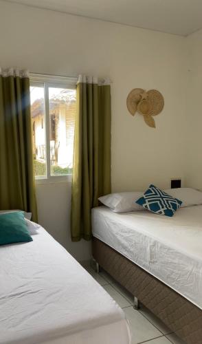 two twin beds in a room with a window at Casa Maré in Aracati