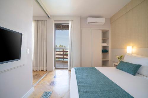 a bedroom with a bed with a television and a balcony at Beach Park Resort - Suites in Aquiraz