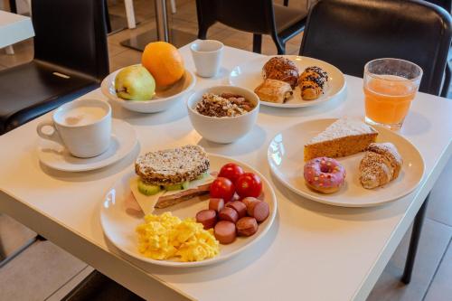 ein Tisch mit Tellern mit Frühstücksspeisen und Getränken in der Unterkunft B&B Hotel Firenze Novoli in Florenz