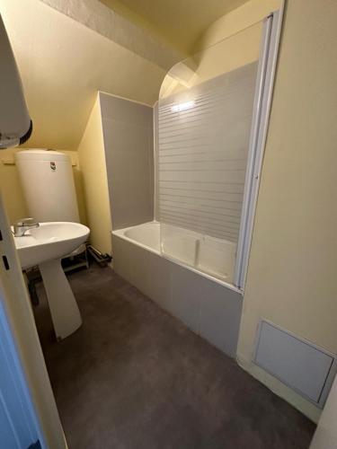 a bathroom with a bath tub and a sink at Hôtel de la gare - Chambre standard in Tarbes