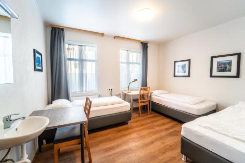 a room with two beds and a sink and a table at Guesthouse Aurora in Reykjavík
